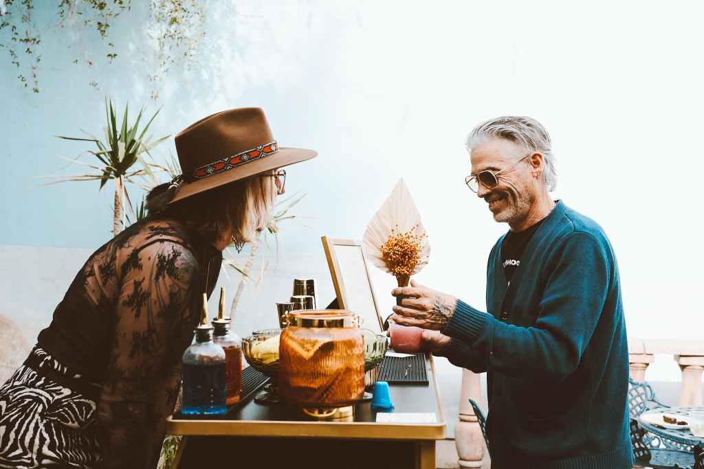 Professional mixologist in a blue cardigan serving a signature pink cocktail at a luxury mobile bar in Scottsdale.