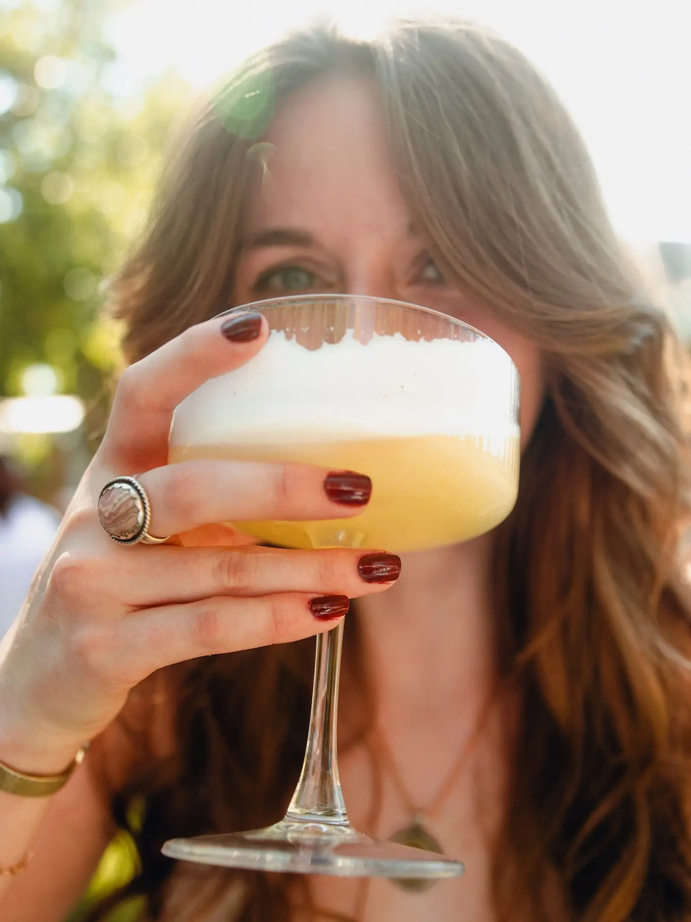 Guest holding a freshly made cocktail with a frothy garnish at an All About It event in Phoenix.