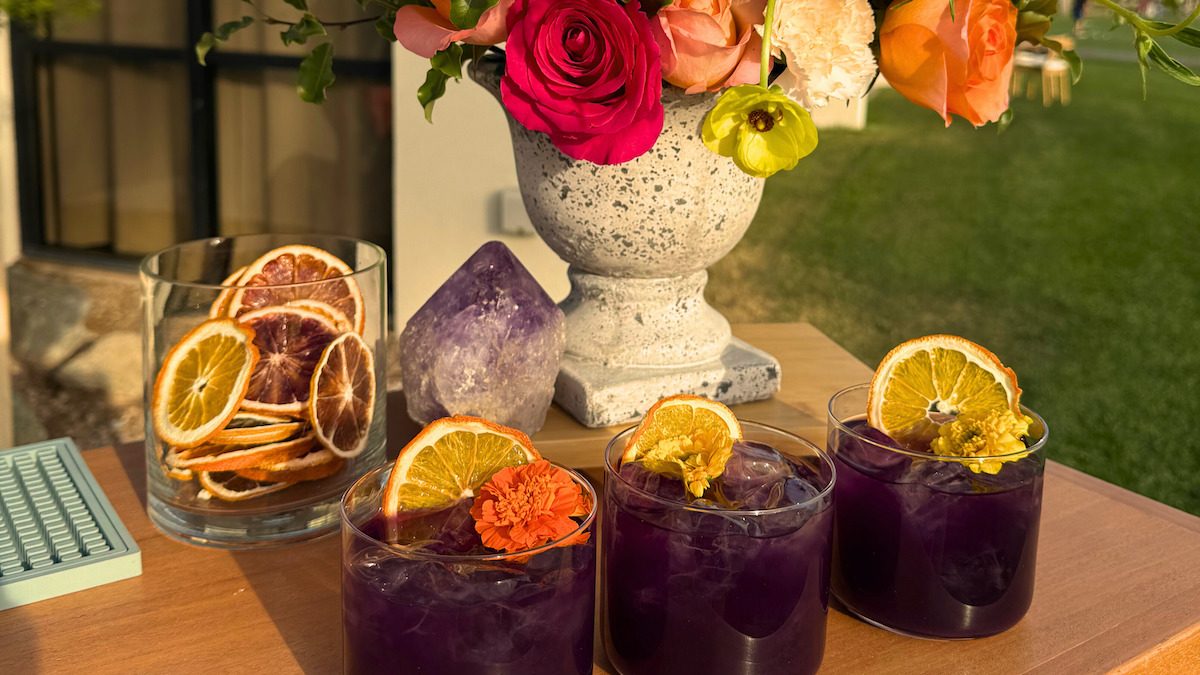Purple craft cocktails with dried citrus garnishes on a mobile bar setup